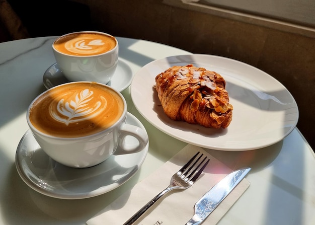 Duas xícaras de café com leite quente com croissant