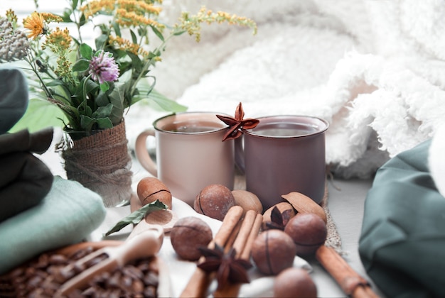 Duas xícaras de café com nozes de macadâmia e canela em um fundo de cobertores