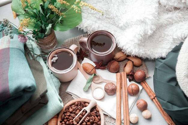 Duas xícaras de café com nozes de macadâmia e canela em um fundo de cobertores