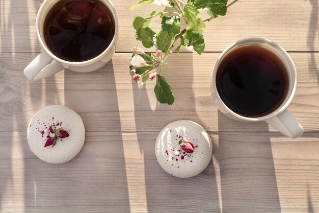 Duas xícaras de café de porcelana com sobremesa de mousse com macieira rosa em flor na mesa de madeira