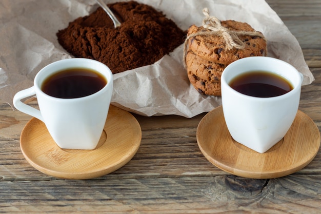 Duas xícaras de café expresso acabado de fazer na mesa de madeira. grãos de café na mesa de madeira clara, estilo rústico, caseiro.