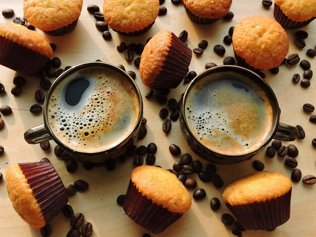 Duas xícaras de café expresso, mini muffins, grãos de café.