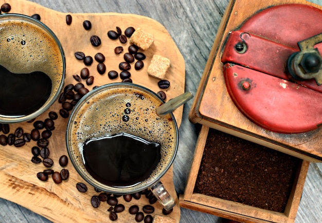 Duas xícaras de café, grãos de café, açúcar granulado marrom e moedor de café