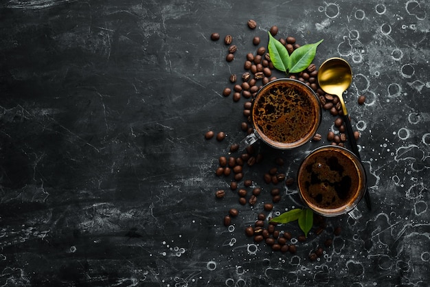 Duas xícaras de café perfumado e grãos de café em um fundo de pedra preta Vista superior Espaço livre para texto