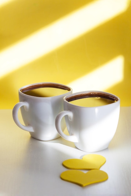 Duas xícaras de café preto sobre fundo amarelo ensolarado Feliz adorável conceito de manhã