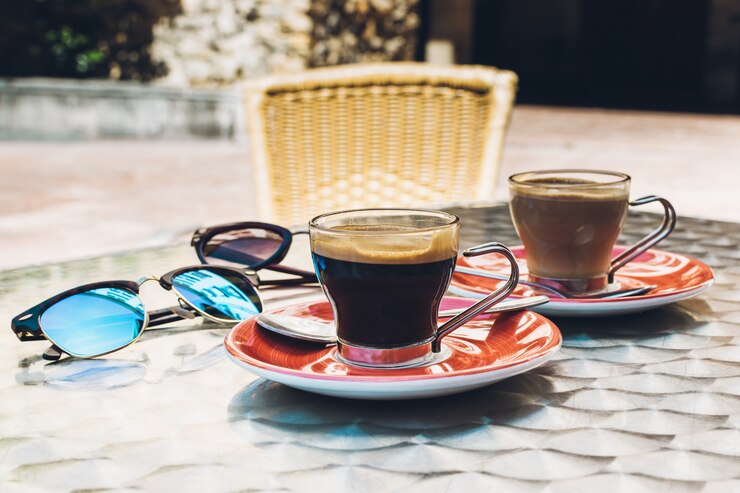 Duas xícaras de café spresso em um terraço. Um par de óculos em uma mesa de metal