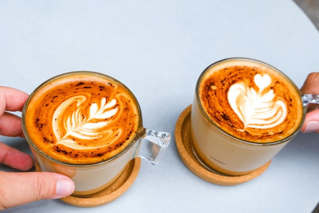 Duas xícaras de cappuccino com latte art no fundo da mesa branca