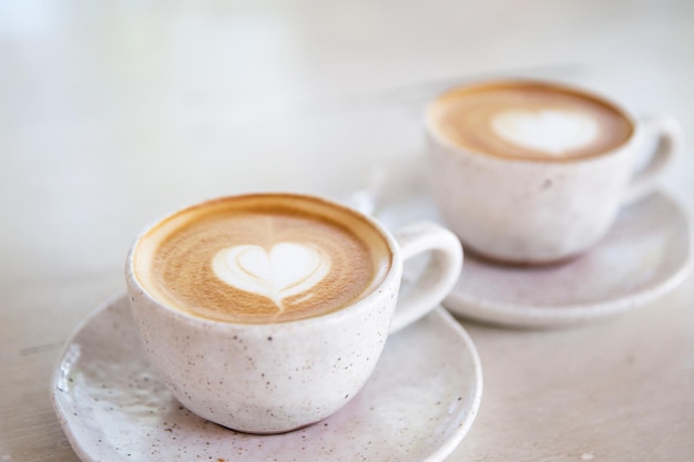 Duas xícaras de cappuccino quente no fundo da mesa de madeira branca