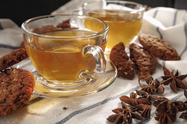 Duas xícaras de chá de ervas e biscoitos em pano de cozinha