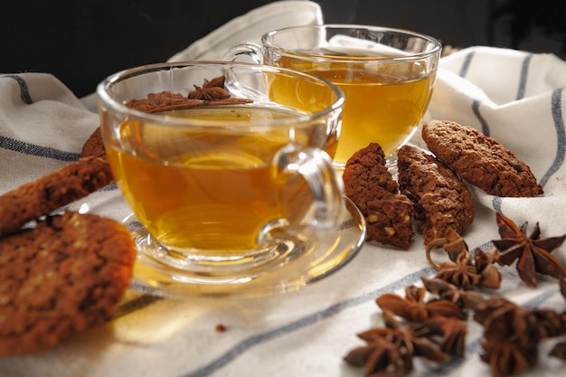 Duas xícaras de chá de ervas e biscoitos no pano de cozinha