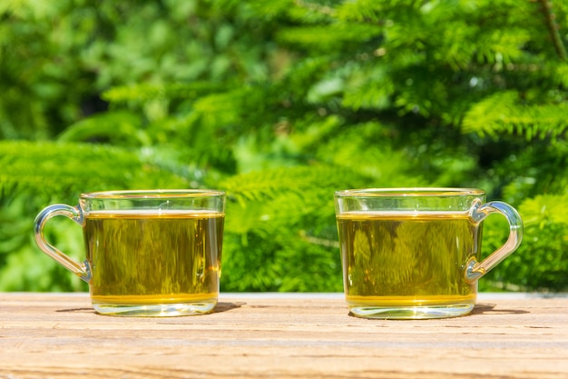 Duas xícaras de chá verde na mesa ao ar livre em um dia de verão ensolarado, em um verde natural