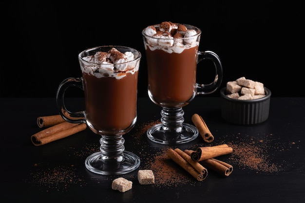 Duas xícaras de chocolate quente ou bebida quente com marshmallow em fundo escuro