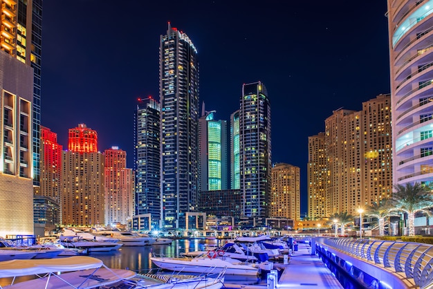 Dubai Marina à noite com arranha-céus, barcos e reflexos na água, Emirados Árabes Unidos