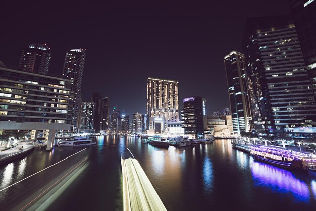 Dubai Marina de noche con rascacielos, barcos y reflejos en el agua, Emiratos Árabes Unidos