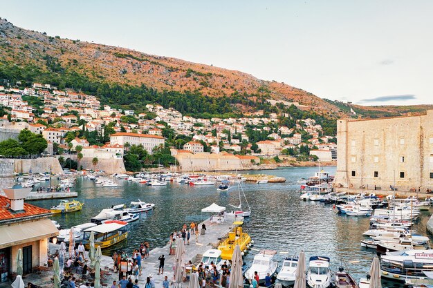 Dubrovnik, Croacia - 19 de agosto de 2016: Noche en la Fortaleza de San Juan y veleros y gente en el puerto viejo en el mar Adriático en Dubrovnik, en Croacia