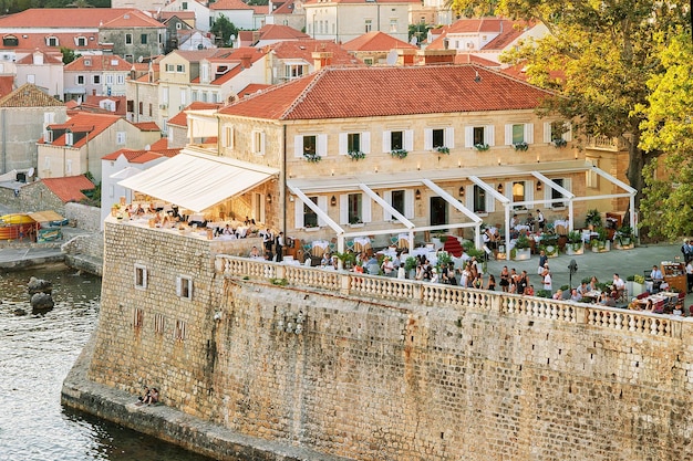 Dubrovnik, Croácia - 19 de agosto de 2016: Pessoas no restaurante com terraço Open Street em Dubrovnik, na Croácia. Vista das muralhas defensivas da cidade. No pôr-do-sol