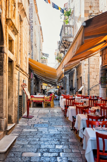 Dubrovnik, Croacia - 20 de agosto de 2016: Café con terraza en la calle en la ciudad vieja de Dubrovnik, Croacia. gente en el fondo