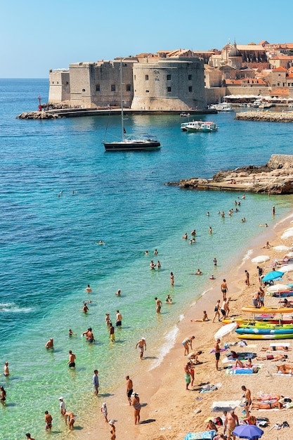 Dubrovnik, Croacia - 20 de agosto de 2016: Playa llena de gente y fuerte de Dubrovnik en el mar Adriático, Croacia