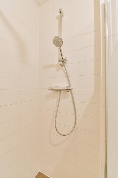 una ducha con azulejos blancos en las paredes y el suelo en un pequeño área de baño que está limpia y lista para que los huéspedes la usen