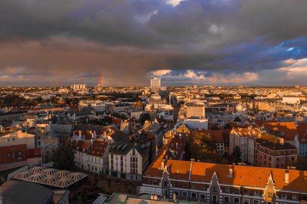 Ducha de lluvia sobre Riga, Letonia al atardecer. Vista aérea del casco antiguo de Riga al atardecer con nubes tormentosas y lluvia ligera en la luz del sol. Tormenta mágica sobre la ciudad. Letonia hermosa.