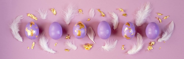 Foto dued huevo de pascua violeta o muy peri con lámina dorada y plumas sobre fondo violeta