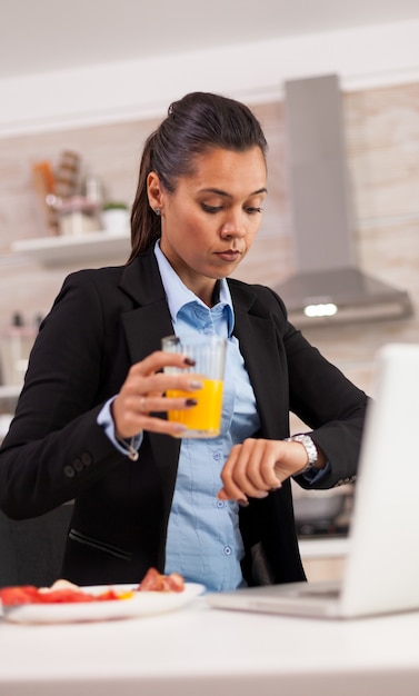 Dueña de la empresa mirando su reloj y maravillándose de la hora tardía