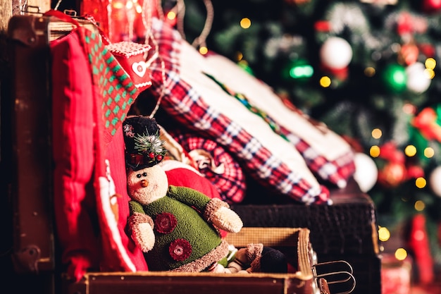 Duende de juguete de Navidad sentado en la maleta en el fondo del árbol de Navidad.