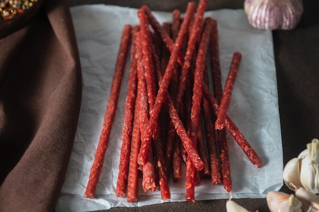 Dünne, appetitliche, würzige Räucherwürste mit Kräutergewürzen und Knoblauch auf dunklem Hintergrund