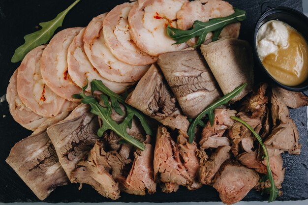 Dünne Fleisch-, Schinken- und Speckscheiben liegen auf einem weißen Teller. Das Fleisch wird auf Zahnstocher gepflanzt, Proben von Produkten zum Testen.