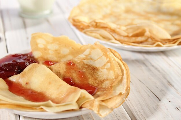 Dünne heiße Pfannkuchen mit Erdbeermarmelade auf einem weißen Holztisch Urlaub Maslenitsa