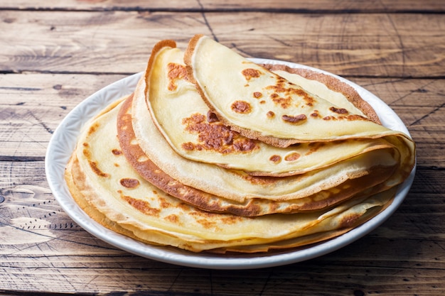 Dünne Pfannkuchen auf einem Teller. Hölzerner Hintergrund Nahansicht.