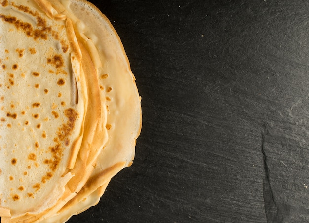 Dünne Pfannkuchen auf schwarzem Hintergrund