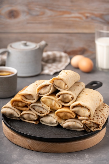 Foto dünne pfannkuchen gefüllt mit hüttenkäse auf eisenpfanne