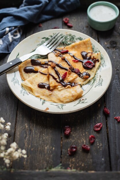 Dünne Pfannkuchen gießen Schokoladenkreppsirup weißen Teller flachen Kuchen