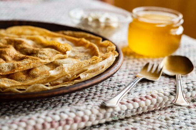 Foto dünne pfannkuchen in einem teller, sauerrahm und honig