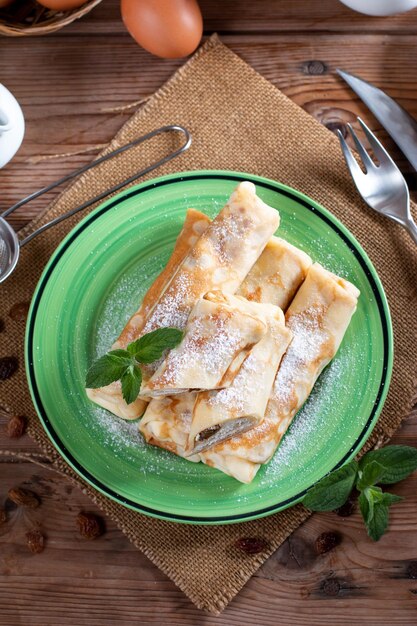 Dünne Pfannkuchen mit Hüttenkäse und Rosinen auf Holztisch Gesundes traditionelles Frühstückskonzept