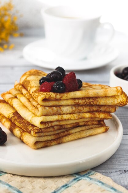 Dünne Pfannkuchen mit mit Himbeere und Johannisbeere auf Teller russisches traditionelles Dessert für Fastnachtfeier Maslenitsa French Crepes