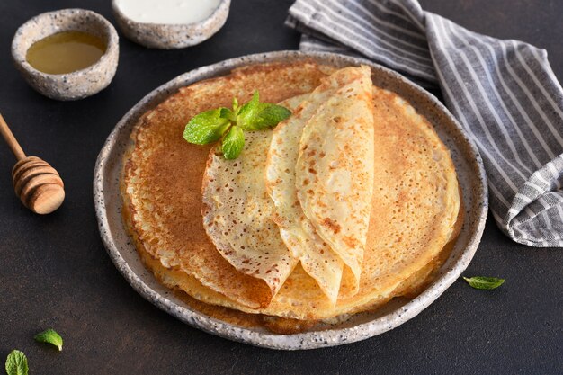 Dünne Pfannkuchen mit saurer Sahne und Honig Stapel Pfannkuchen.