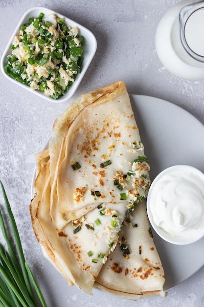 Dünne Pfannkuchen oder Crepes mit Ei, Frühlingszwiebeln und Sauerrahm