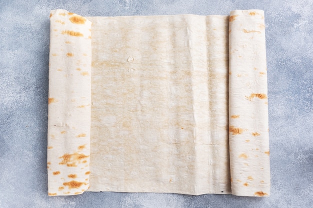 Dünner armenischer Lavash rollte zu einer Rolle. Textur des natürlichen Brotbackens.