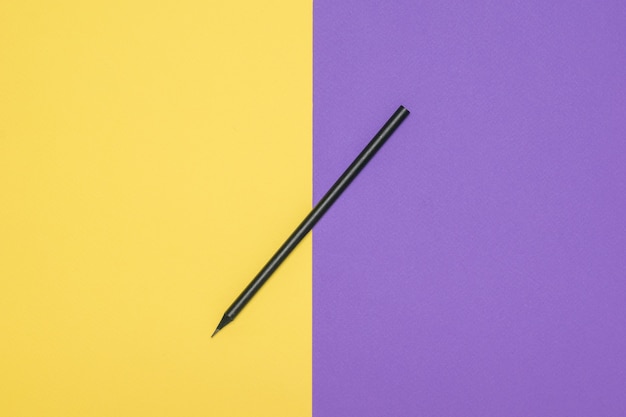 Dünner schwarzer Stift auf gelbem und lila Hintergrund. Stilvolles Briefpapier.