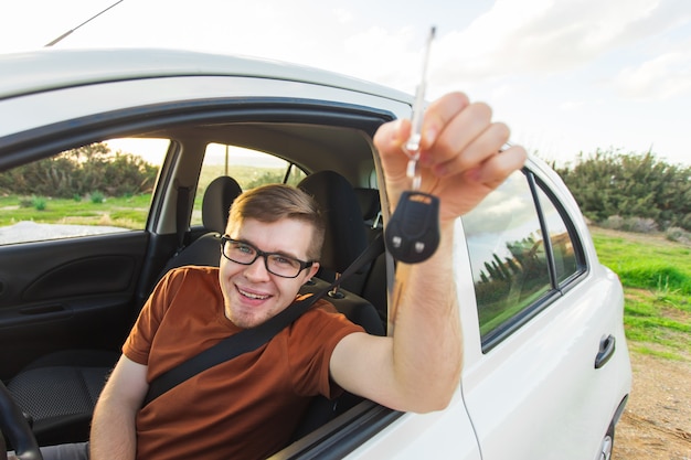 Dueño de auto feliz está mostrando la llave dentro de su auto nuevo.