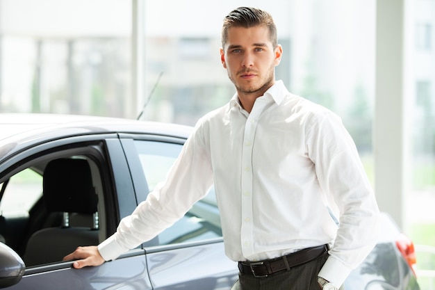 El dueño del auto feliz está mostrando los pulgares hacia arriba y la nueva llave de su auto