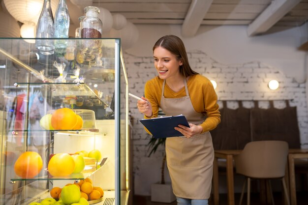 El dueño de un café busca postres disponibles en el mostrador.