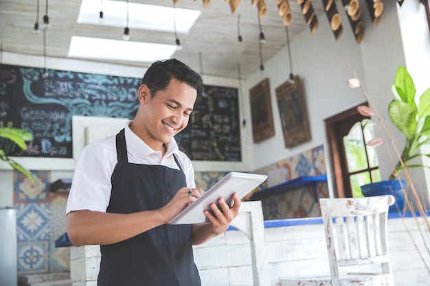 Dueño de café masculino joven con tableta