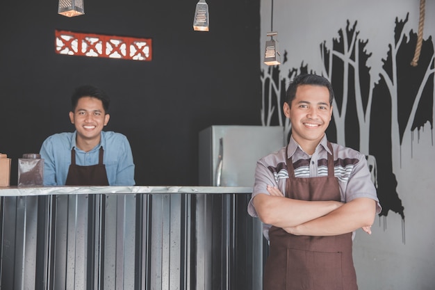 Dueño del café de pie con los brazos cruzados