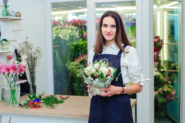 El dueño de una florería hace un ramo de rosas blancas.