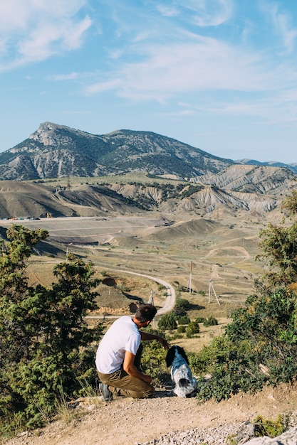 Dueño masculino de perro spaniel caminando contra el fondo de las montañas