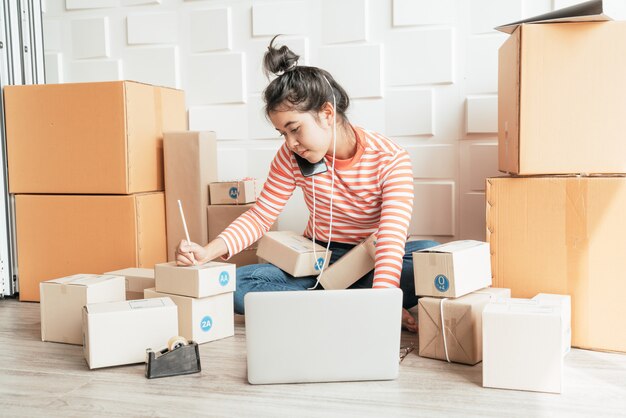 Dueño de un negocio de mujeres asiáticas trabajando en casa con caja de embalaje en el lugar de trabajo