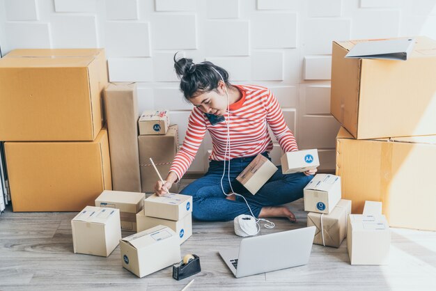 Dueño de un negocio de mujeres asiáticas trabajando en casa con caja de embalaje en el lugar de trabajo